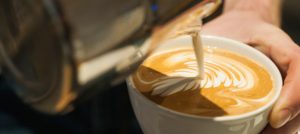 milk being poured into a coffee cup